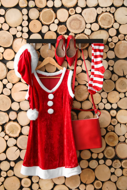 Vrouwelijke kostuum van de Kerstman met stijlvolle accessoires opknoping op houten muur - Foto, afbeelding