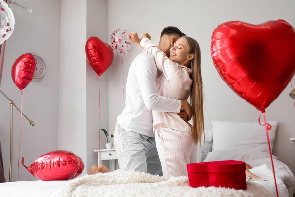 Счастливая пара празднует День святого Валентина в спальне дома - Фото, изображение