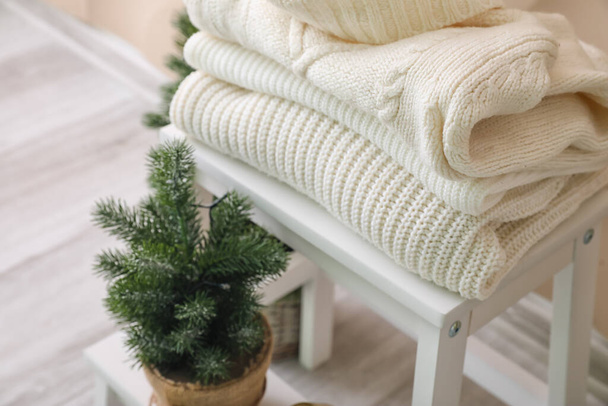 Крокові драбини з теплими зимовими светрами і ялиновим деревом в кімнаті
 - Фото, зображення