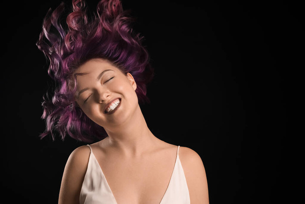 Portrait of happy young woman with unusual hair on black background - Photo, Image
