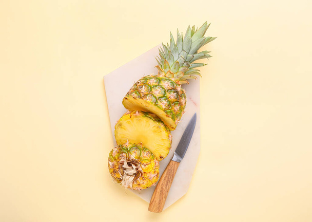 Placa com abacaxi cortado e faca no fundo de cor - Foto, Imagem