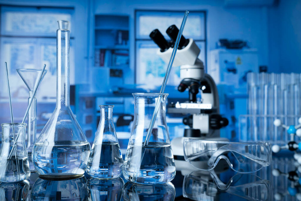 Investigaciones de laboratorio sobre la prueba y la medicina contra el covidio. Microscopio, tubos de vidrio y vasos de precipitados en el laboratorio. - Foto, imagen
