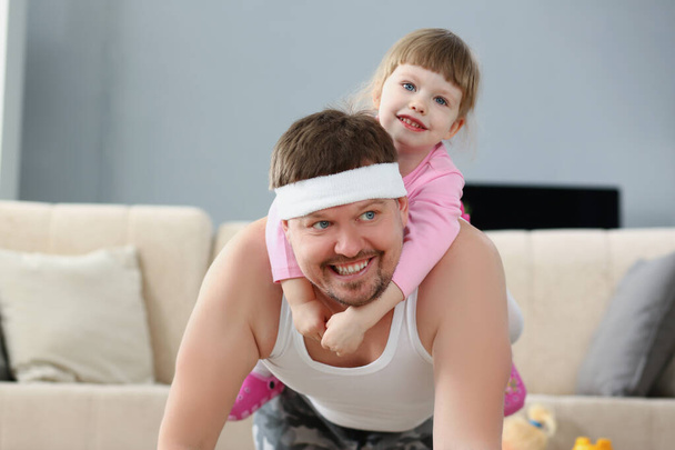 Πατέρας και κόρη περνούν χρόνο στο σπίτι, αθλητική δραστηριότητα με το παιδί στην πλάτη - Φωτογραφία, εικόνα