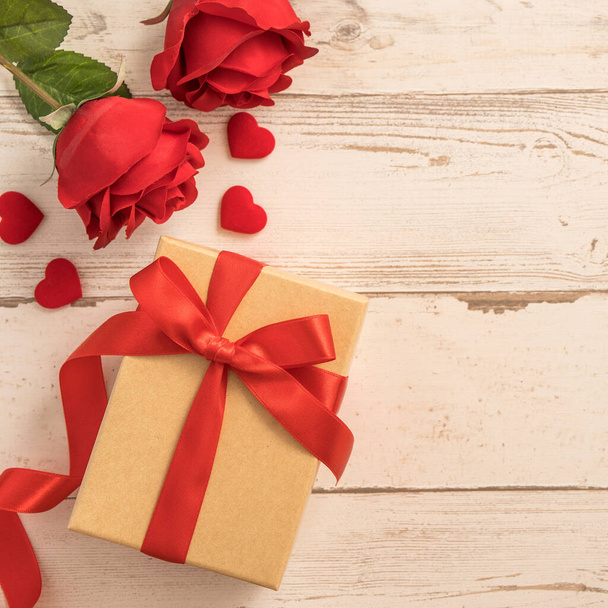 Kraft gift box with red ribbon bow, concept of giving present and Valentine's, anniversary, mother's day and birthday surprise, flat lay, top view - 写真・画像