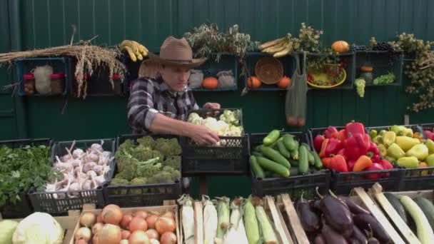 Cauliflower at the farmers' market.A male salesman places a box of cauliflower on the counter and then looks into the camera.The camera moves smoothly along the boxes with a variety of vegetables. - Filmmaterial, Video