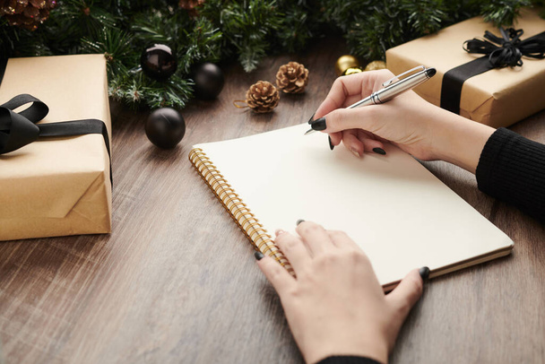 Glose-up image of woman writing wish list of presents she wants to receive for Christmas - Photo, Image
