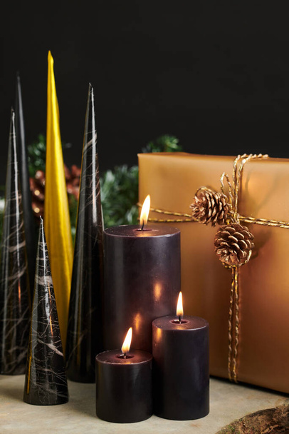 Černé hořící svíčky, vánoční dárky a papírové kornouty z černého a zlatého papíru - Fotografie, Obrázek