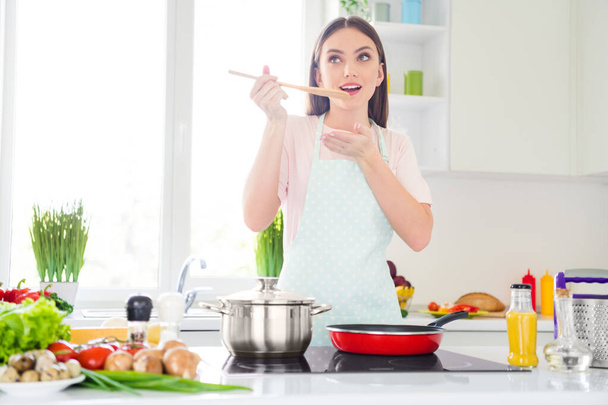 Portrait of attractive cheery dreamy girl preparing weight loss dinner tasting delicious meal at home light white kitchen indoors - Fotoğraf, Görsel