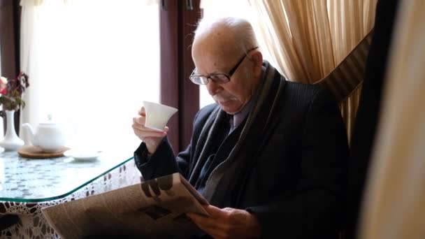 Ένας συνταξιούχος διαβάζει εφημερίδα με καφέ.. - Πλάνα, βίντεο