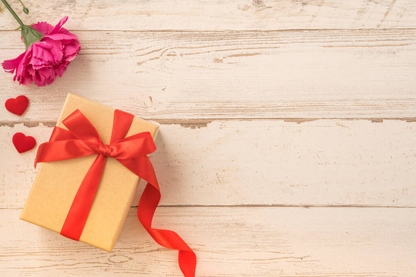 Крафт подарочная коробка с красной лентой лук и гвоздика, концепция дарения подарок на День матери, как сюрприз, плоский лежал, вид сверху - Фото, изображение