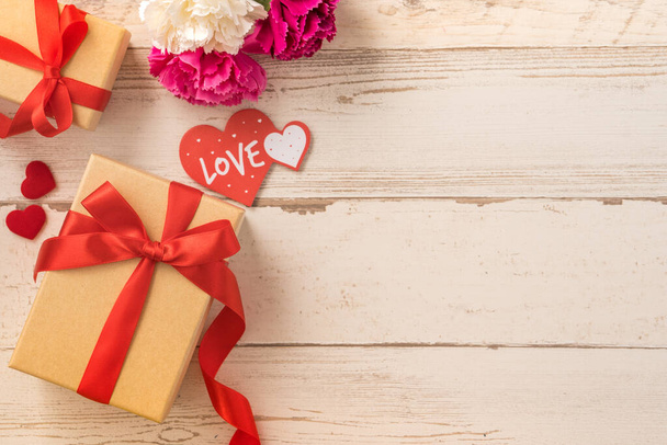 Caja de regalo Kraft con lazo de cinta roja y clavel, concepto de dar regalo en el día de la madre como sorpresa, laico plano, vista superior - Foto, imagen