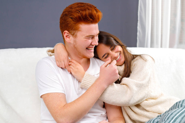 Cheerful married couple resting on couch enjoy lazy weekend together at home having fun over white and grey background. - Photo, image