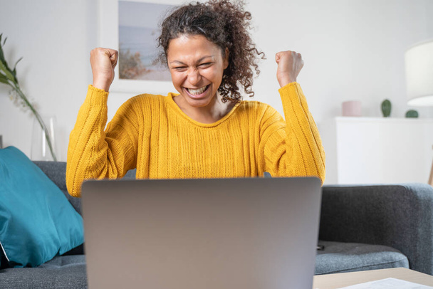 Щаслива чорна жінка, що святкує онлайн перемогу вдома
 - Фото, зображення