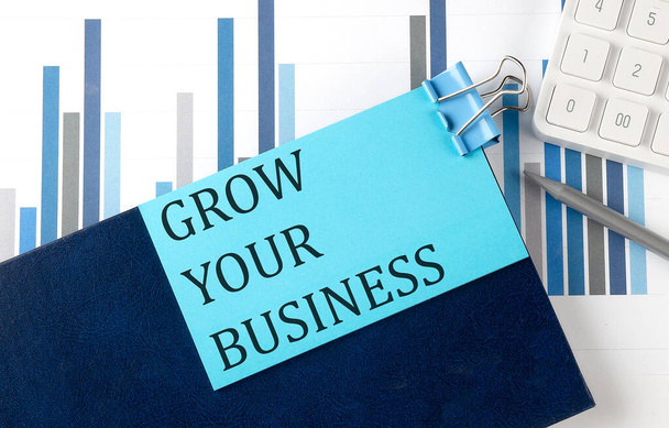 GROW YOUR BUSINESS on sticky note on the notebook on the chart background - Photo, image