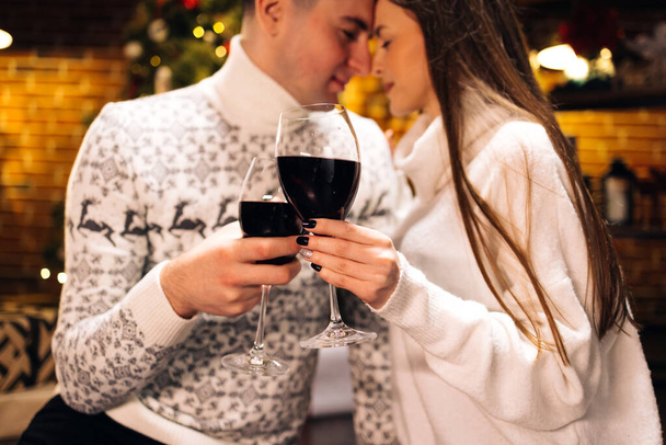Love romance holiday celebration concept. Couple holding and drinking wine glasses sitting on sofa. Joy female and male toasting with red wine - Foto, imagen