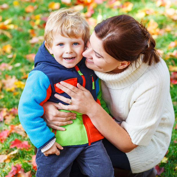 νεαρή μαμά και τον μικρό γιο παιδί αγκάλιασμα μαζί στο πάρκο φθινόπωρο - Φωτογραφία, εικόνα