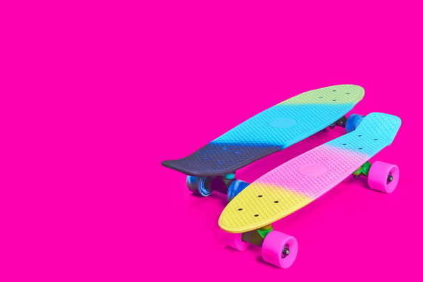 Two rainbow plastic Penny board skateboards on crimson background - Photo, Image