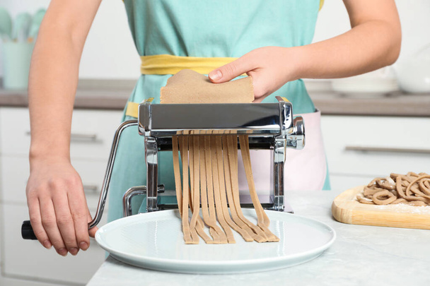 Woman preparing soba (buckwheat noodles) with pasta maker machine in kitchen, closeup - Foto, immagini