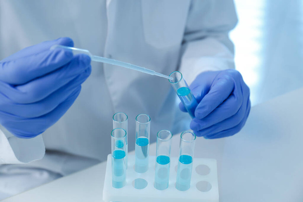 Scientist dripping sample into test tube in laboratory, closeup. Medical research - Φωτογραφία, εικόνα