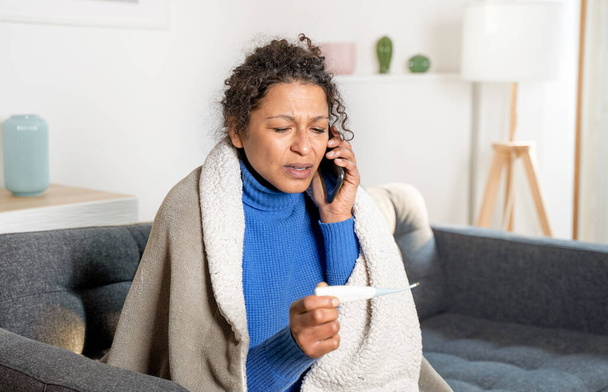 Portrait of sick black woman calling doctor from home - Photo, Image