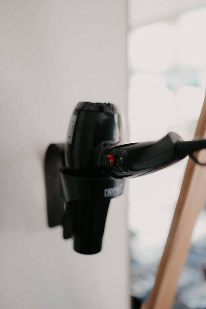 A selective focus shot of a blow dryer in a holder on the wall - Foto, immagini