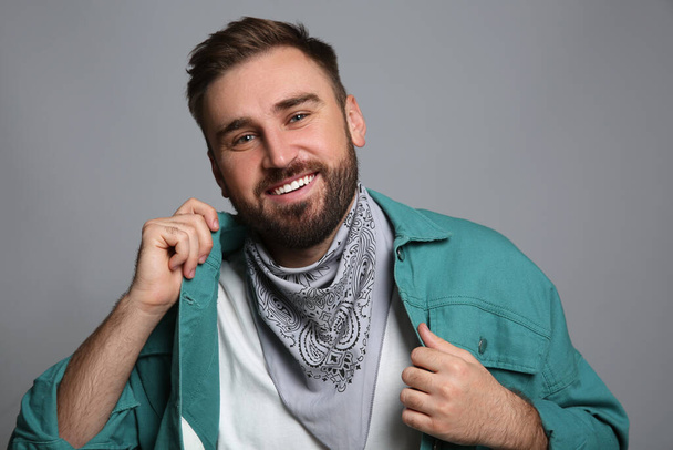 Fashionable young man in stylish outfit with bandana on grey background - Foto, afbeelding