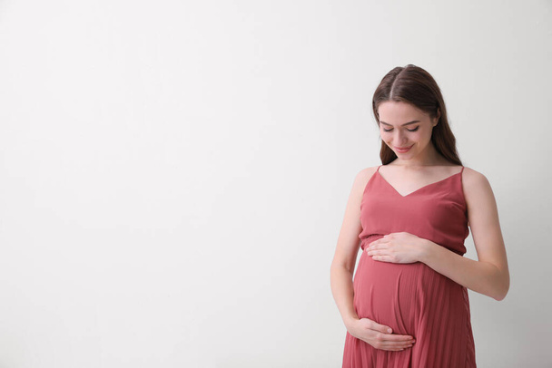 Beautiful young pregnant woman on light background. Space for text - Valokuva, kuva