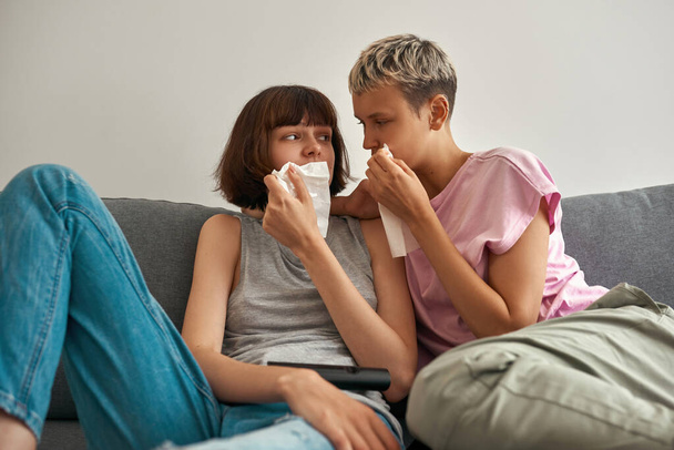Young sad lesbians watching TV and crying on sofa - Zdjęcie, obraz