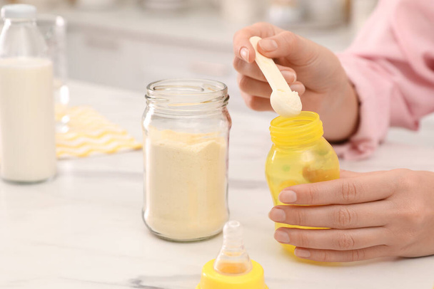 Woman preparing infant formula at table indoors, closeup. Baby milk - Fotoğraf, Görsel