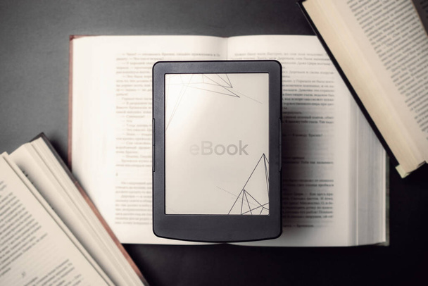 Читатели. Цифровая электронная книга, планшет читателя библиотеки с книгами на темном фоне. Электронная книга, электронное обучение, концепция интернет-мобильности - Фото, изображение