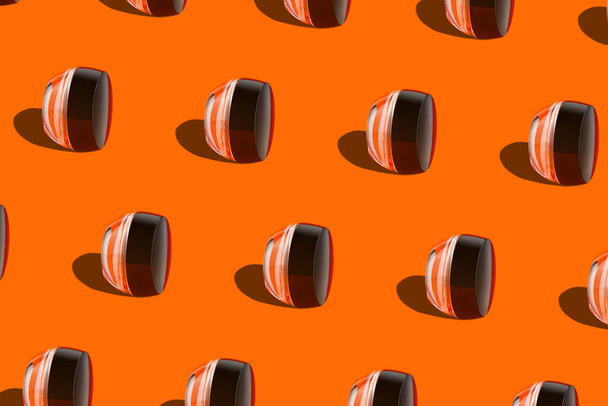 化粧パターン顔クリームトーンファンデーションガラス瓶幾何学的な表彰台オレンジの背景。化粧品パッケージのバランスをとる滑らかなBB液体顔の皮膚。スキントーン補正｜モダンミニマルなコンテンツ - 写真・画像