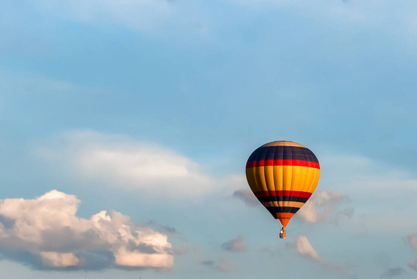 un globo de colores brillantes en el cielo azul sobre un fondo de nubes blancas - Foto, Imagen