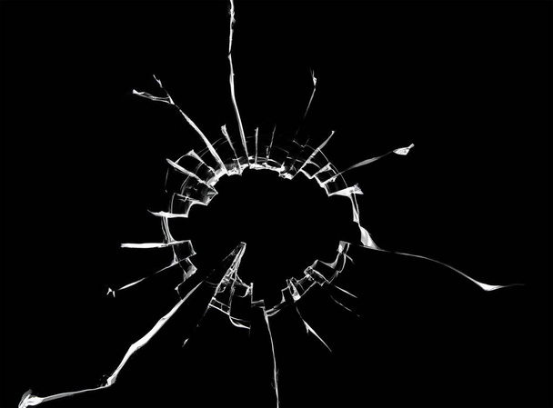 Texture of cracks on the window, broken glass with a hole on a black background - Foto, Bild