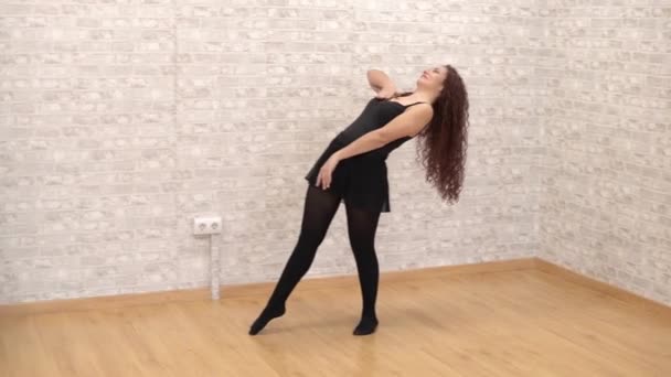 Beautiful young woman dancer training classical contemporary dance in a dance studio alone - Filmati, video