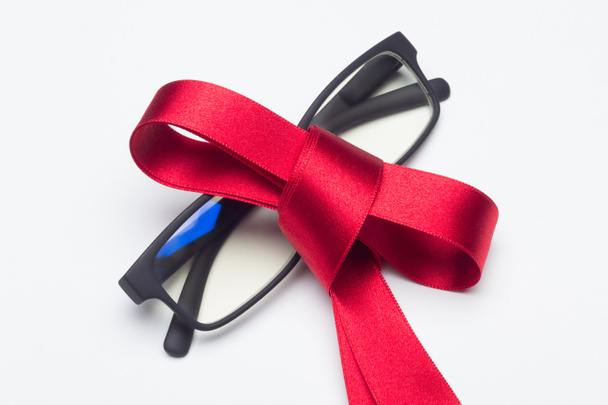Óculos pretos com arco vermelho para dar como presente no fundo branco - Foto, Imagem