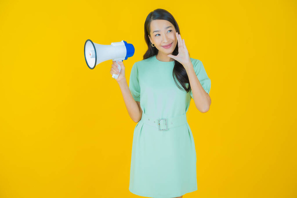 Portrait beautiful young asian woman smile with megaphone on color background - Фото, изображение