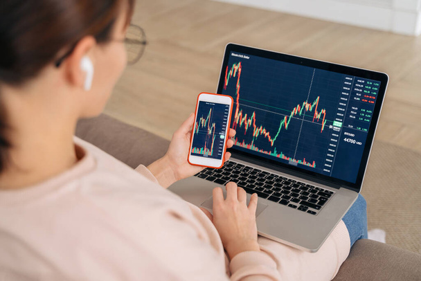 Primer plano de la mujer de negocios inversor analista mirando gráficos del mercado de valores financieros tasa dinámica, utilizando el ordenador portátil y aplicación de teléfono inteligente para el análisis digital criptomoneda, la compra de criptomoneda - Foto, Imagen