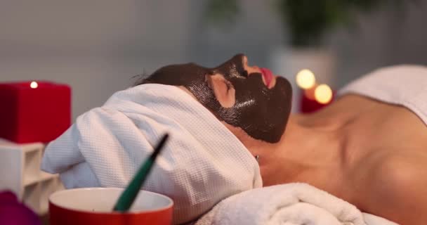 Mujer con máscara de barro negro en su cara se encuentra en el spa 4k película - Imágenes, Vídeo