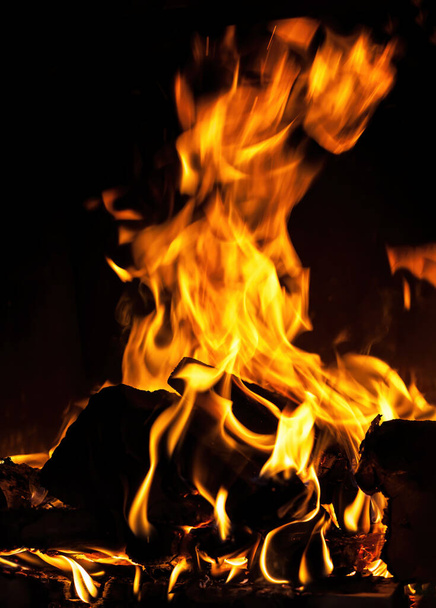Flames, fire background and texture. Fireplace with wood and fire on a dark background - Fotó, kép