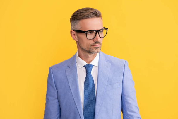 adult businessman in elegant jacket and eyeglasses on yellow background, business vision - 写真・画像