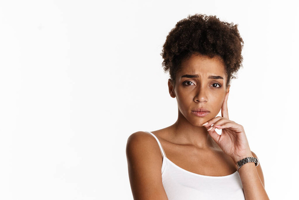 Young black woman in tank top frowning and looking at camera isolated over white background - Фото, изображение
