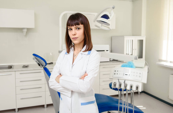 Mujer joven dentista médico en medio de la clínica médica mirando a la cámara - Foto, Imagen
