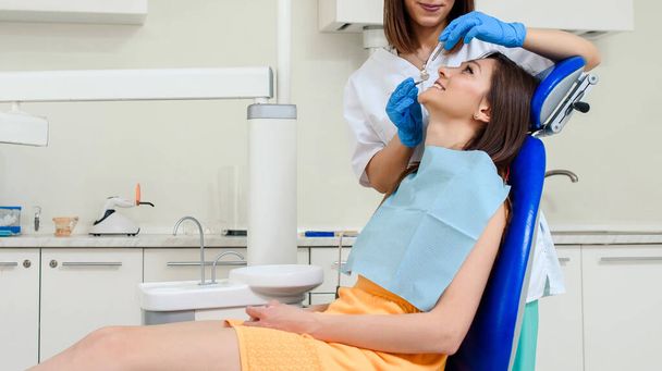 Genç kadın hasta dişçi kliniğinde diş tedavisi görüyor. - Fotoğraf, Görsel