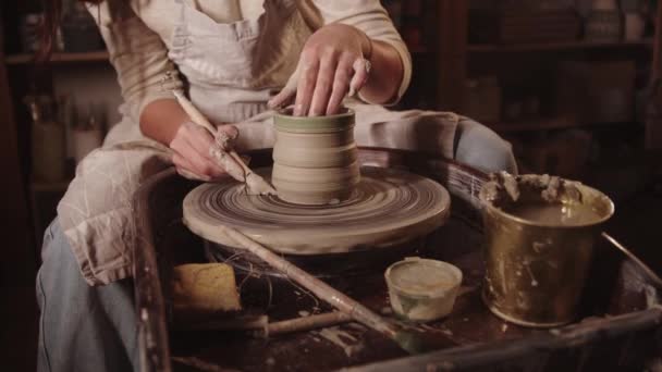 Giovane donna vasaio tagliare l'eccesso di pentola di argilla - Filmati, video