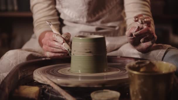 Jonge vrouw pottenbakker maken van bruggen op de natte pot met behulp van een gereedschap - Video