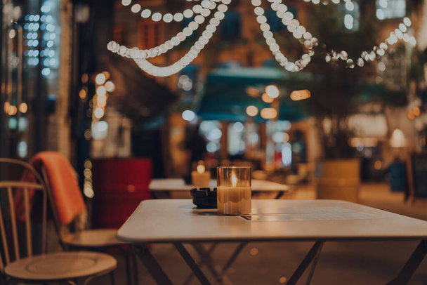 Lite up kaars aan een outdoor tafel van een restaurant in de winter, gezellige sfeer, selectieve focus, bokeh. - Foto, afbeelding