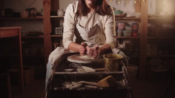 若い女性の陶芸家は彼女の手を濡らし、彼女の手で粘土を形成し始める - 映像、動画