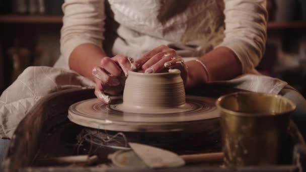 Młoda kobieta garncarka moczy ręce i tworzy glinę palcami - Materiał filmowy, wideo