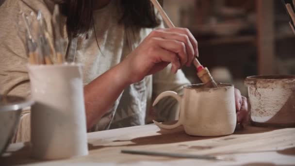 Νεαρή γυναίκα αγγειοπλάστη που εργάζονται σε στούντιο τέχνης - ζωγραφική το τελικό κεραμικό προϊόν από το εσωτερικό - Πλάνα, βίντεο