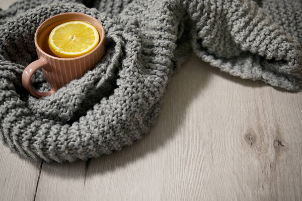Té caliente del invierno en una taza con las virutas del limón y una bufanda  - Foto, imagen